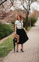 A lady wears a white cardigan and a black maxi skirt.
